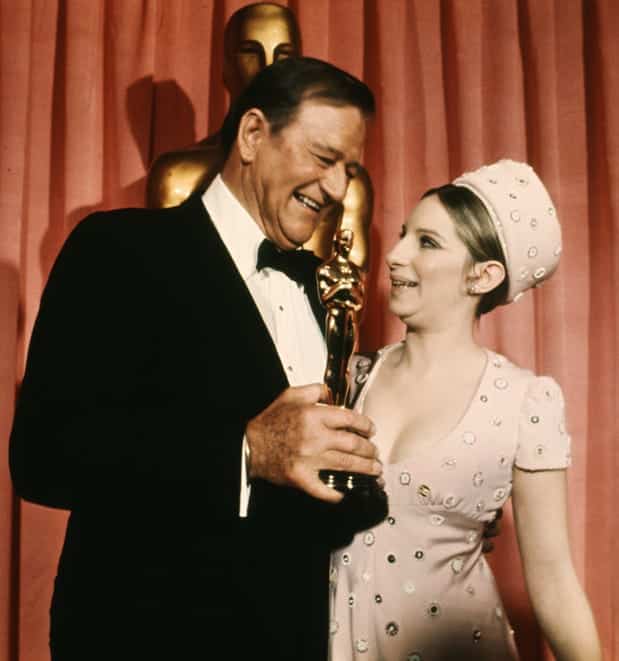 John Wayne stands next to Barbra Streisand with the Oscar he was awarded for "True Grit" in 1970.